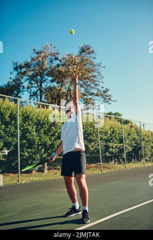 Il est difficile de battre quelqu'un qui ne se délaisse jamais. Un jeune sportif jouant au tennis sur un court de tennis. Banque D'Images