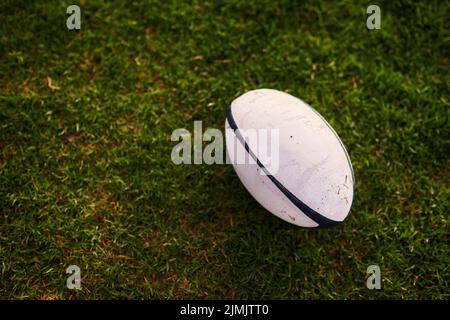 Que les matchs commencent. Un ballon de rugby sur un terrain de rugby vide pendant les premières heures du matin. Banque D'Images