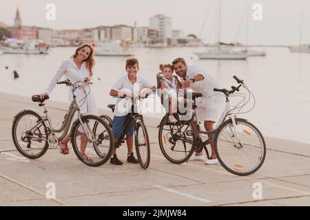 La famille heureuse profite d'une belle matinée au bord de la mer à vélo et à passer du temps ensemble. Le concept d'un heureux Banque D'Images