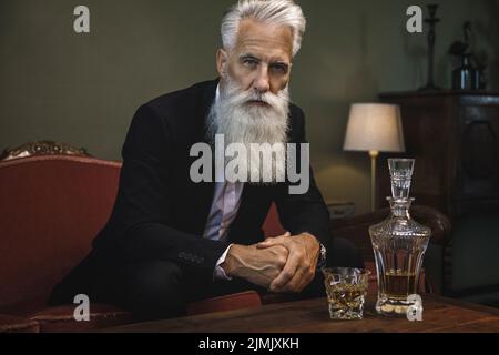 Beau et barbu homme senior buvant du whisky Banque D'Images