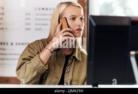 Cette semaine, on attendait tant de clients qu'un jeune coiffeur attrayant qui faisait un appel téléphonique et des réservations à l'intérieur de son salon de coiffure. Banque D'Images