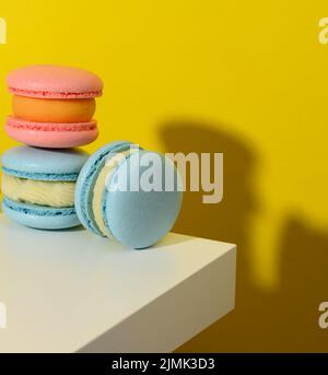 Macarons ronds cuits sur fond jaune, délicieux dessert Banque D'Images