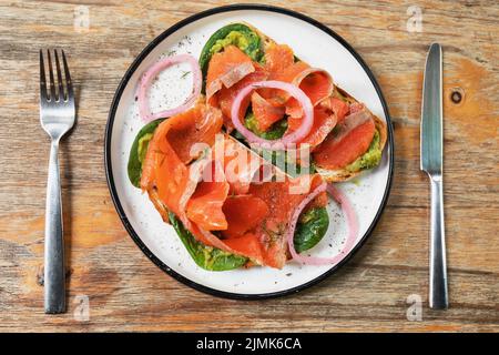 Délicieux toasts avec du saumon fumé, de l'avocat et des feuilles de basilic Banque D'Images