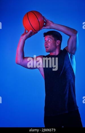 Je ne manque jamais une prise de vue. Prise de vue filtrée rouge d'un sportif jouant au basket-ball en studio. Banque D'Images