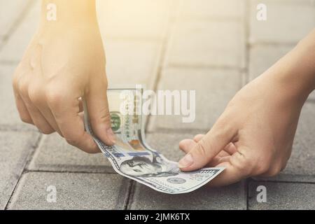 La femme chanceuse a ramassant une facture de cent dollars de la terre. Banque D'Images