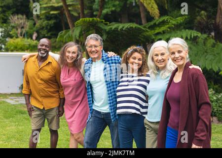 Portrait d'amis multiraciaux âgés et féminins heureux avec des bras autour debout dans l'arrière-cour Banque D'Images