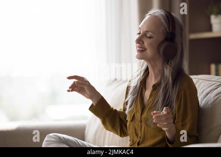 Bonne joyeuse belle dame âgée dans un casque moderne d'avoir du plaisir Banque D'Images