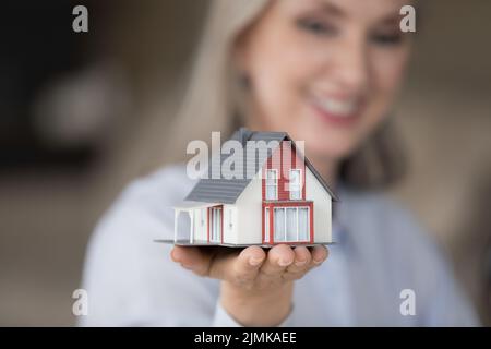 Bonne femme de realtor tenant un modèle de maison minuscule à portée de main Banque D'Images