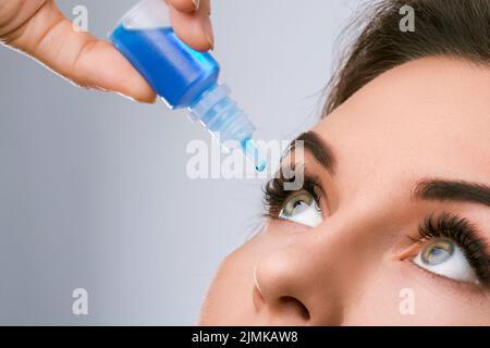 Photo de studio d'une belle femme utilisant des gouttes pour les yeux Banque D'Images