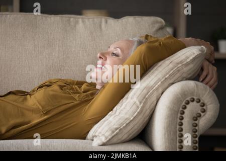 Bonne joyeuse femme mûre couchée sur un canapé confortable Banque D'Images