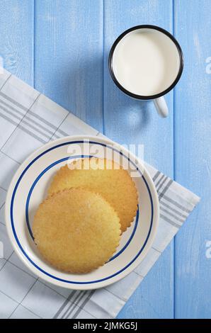 Pain d'épice et tasse de lait en émail sur table en bois bleu, vue du dessus Banque D'Images