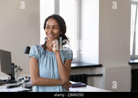 Femme d'affaires africaine pensive souriante qui regarde à distance Banque D'Images