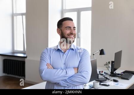 Un homme d'affaires millénaire prospère se pose sur le lieu de travail avec les armes croisées Banque D'Images