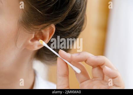 Femme nettoyant l'oreille avec un coton-tige Banque D'Images