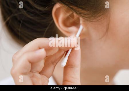 Femme nettoyant l'oreille avec un coton-tige Banque D'Images