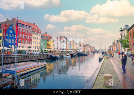 Les gens marchent dans la rue Nyhavn - un endroit populaire pour marcher avec de nombreux bateaux et maisons colorées à Copenhague, Danemark Banque D'Images