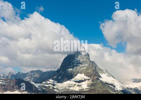 Mont Cervin dans les Alpes Pennines. Un nuage blanc et moelleux se trouve au-dessus d'une montagne par une belle journée d'été. Banque D'Images