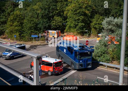 Berlin, Allemagne. 07th août 2022. Des pompiers et des véhicules de police se trouvent près du lieu de l'incendie au site de dynamitage de la police de Berlin à Grunewald. Jeudi 04.08.2022, un incendie avait éclaté sur le site de dynamitage. Le site de dynamitage stocke les munitions que les experts en la matière rendent normalement inoffensives. Malgré l'effet initial des mesures d'extinction, l'incendie au Grunewald de Berlin demeure un « danger énorme » de l'avis du service des incendies. Credit: Christophe bateau/dpa/Alay Live News Banque D'Images