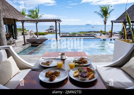 Petit déjeuner sur une plage avec palmiers et piscine à l'île Maurice, cadre tropical avec petit déjeuner Banque D'Images