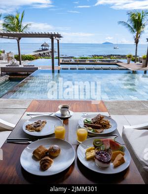 Petit déjeuner sur une plage avec palmiers et piscine à l'île Maurice, cadre tropical avec petit déjeuner Banque D'Images