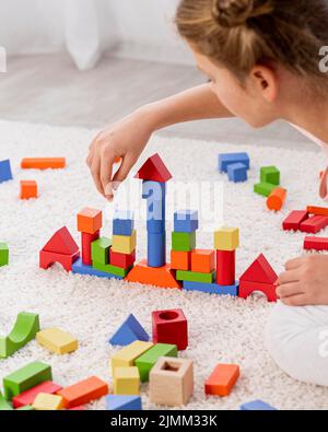 Enfant non binaire jouant avec le jeu coloré à la maison Banque D'Images