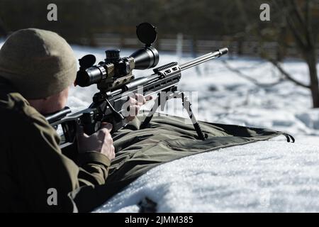 Un fusil de sniper avec une vue optique dans les mains de l'homme aimimg vue arrière jour d'hiver Banque D'Images