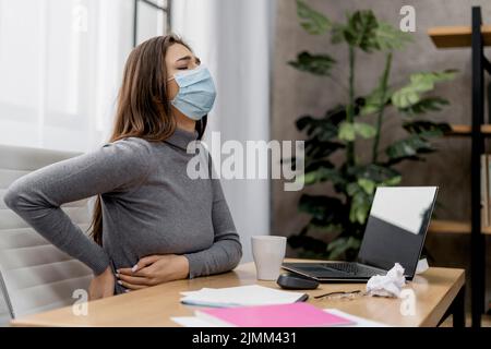 Femme ayant mal de dos pendant qu'elle travaille à la maison Banque D'Images