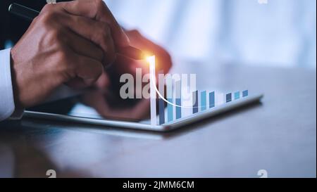 Homme d'affaires écrivant analyser graphique pour le marché boursier sur écran tablette. Graphique à dessin homme d'affaires graphique du stock de croissance. L'homme de main utilise le stylo pour Banque D'Images