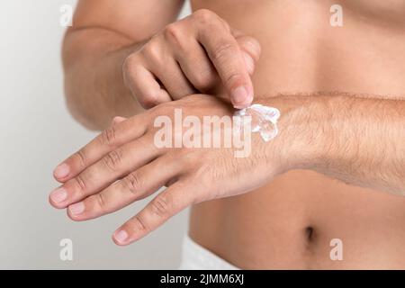 Gros plan homme appliquant la main crème Banque D'Images