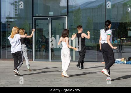 Des adolescents ou de jeunes adultes pratiquant des mouvements de danse devant la bibliothèque Oodi à Helsinki, en Finlande Banque D'Images