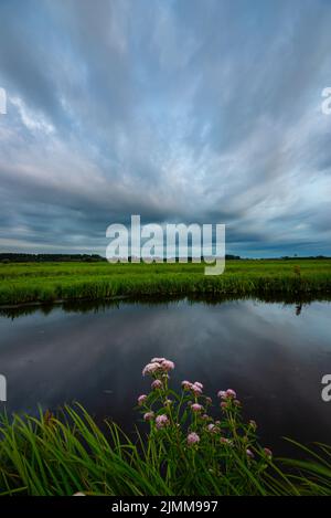 Des nuages spectaculaires se reflètent dans un fossé rempli d'eau dans le paysage de la polder hollandaise près de la ville de Gouda, Hollande Banque D'Images