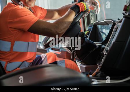 Thème transport lourd. Conducteur de semi-camion caucasien à l'intérieur de la cabine de véhicule en gardant les mains sur un volant de direction. Banque D'Images