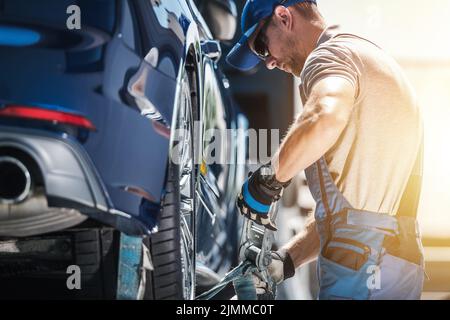 Un travailleur de remorquage caucasien attache un véhicule cassé à l'aide de sangles d'arrimage. Assistance routière professionnelle et services de couverture en cas de panne. Automobile an Banque D'Images