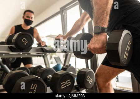 Jeune homme sportif portant un masque de prévention pendant son entraînement en salle de gym Banque D'Images
