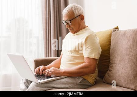 Un homme âgé utilise un ordinateur portable à la maison Banque D'Images