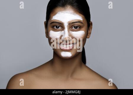 Jeune femme indienne avec un masque de nettoyage appliqué sur son visage Banque D'Images