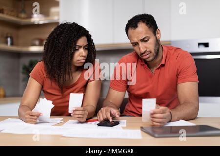 Malheureux bouleversé couple afro-américain millénaire dans les mêmes t-shirts compte des factures, travailler avec des documents Banque D'Images