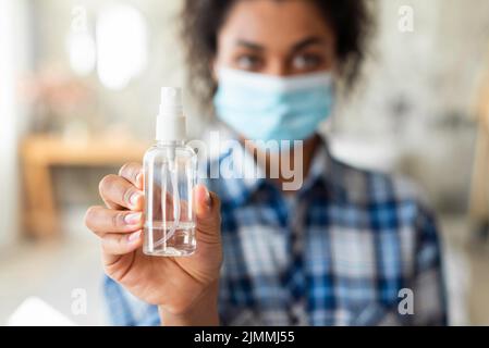 Femme défocusée avec un masque médical tenant un désinfectant pour les mains Banque D'Images