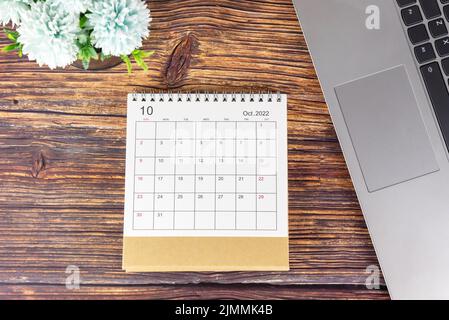 Calendrier d'octobre 2022 sur table rustique en bois avec clavier pour ordinateur portable et fleurs bleues. Calendrier de mise en place professionnelle. Mois de novembre 2022 Banque D'Images