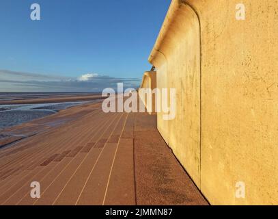 Vue en perspective sur le sentier côtier en béton de blackpool avec des marches menant à la plage dans la lumière chaude de l'après-midi avec du bleu Banque D'Images