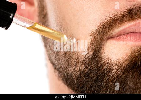 Visage masculin et pipette avec une huile pour une croissance de la barbe Banque D'Images