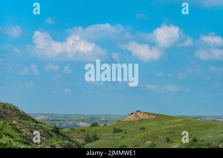 Un troupeau de chevaux sauvages se repose sur une corniche dans le vaste paysage du parc national Theodore Roosevelt dans le Dakota du Nord pendant une journée d'été avec le cumulus Banque D'Images