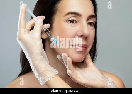 Femme d'âge moyen recevant une injection faciale pour rajeunir la peau Banque D'Images