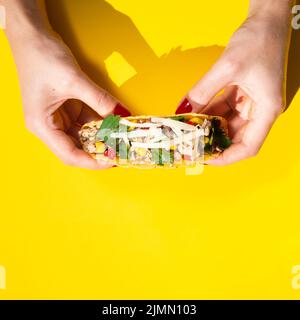 Gros plan des mains tenant le taco sur fond jaune Banque D'Images
