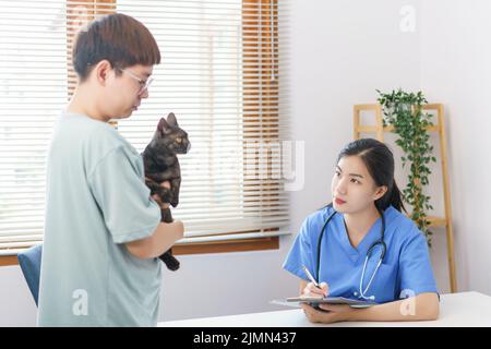 Concept de soins pour animaux de compagnie, le vétérinaire féminin écrit la prescription sur le presse-papiers après examen de santé chat. Banque D'Images