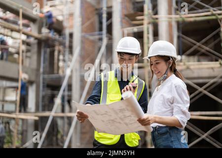 les responsables de l'ingénierie et de la construction discutent de l'impression bleue du projet sur le table sur le chantier Banque D'Images