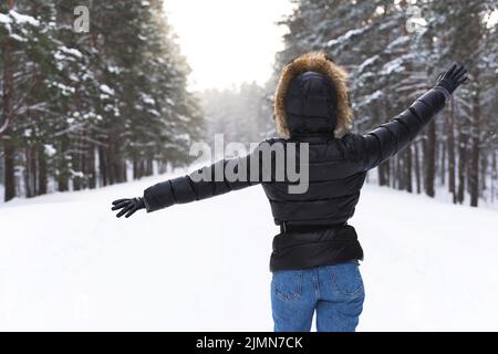 Femme portant une veste en duvet avec une capuche marchant dans le parc pendant la journée froide d'hiver Banque D'Images