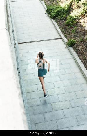 Une femme sportive court rapidement pendant son entraînement de rue Banque D'Images