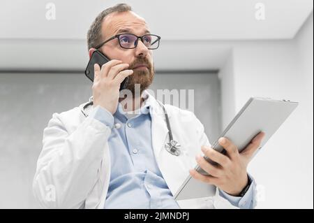 Médecin au bureau parlant au téléphone Banque D'Images