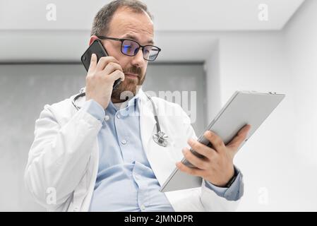 Médecin au bureau parlant au téléphone Banque D'Images